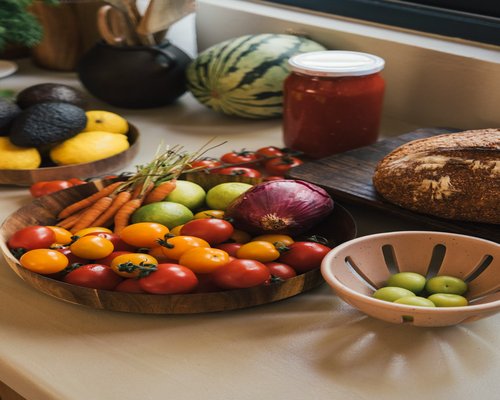 A variety of colorful fresh vegetables like avocados and lemons neatly placed on a bright kitchen counter
